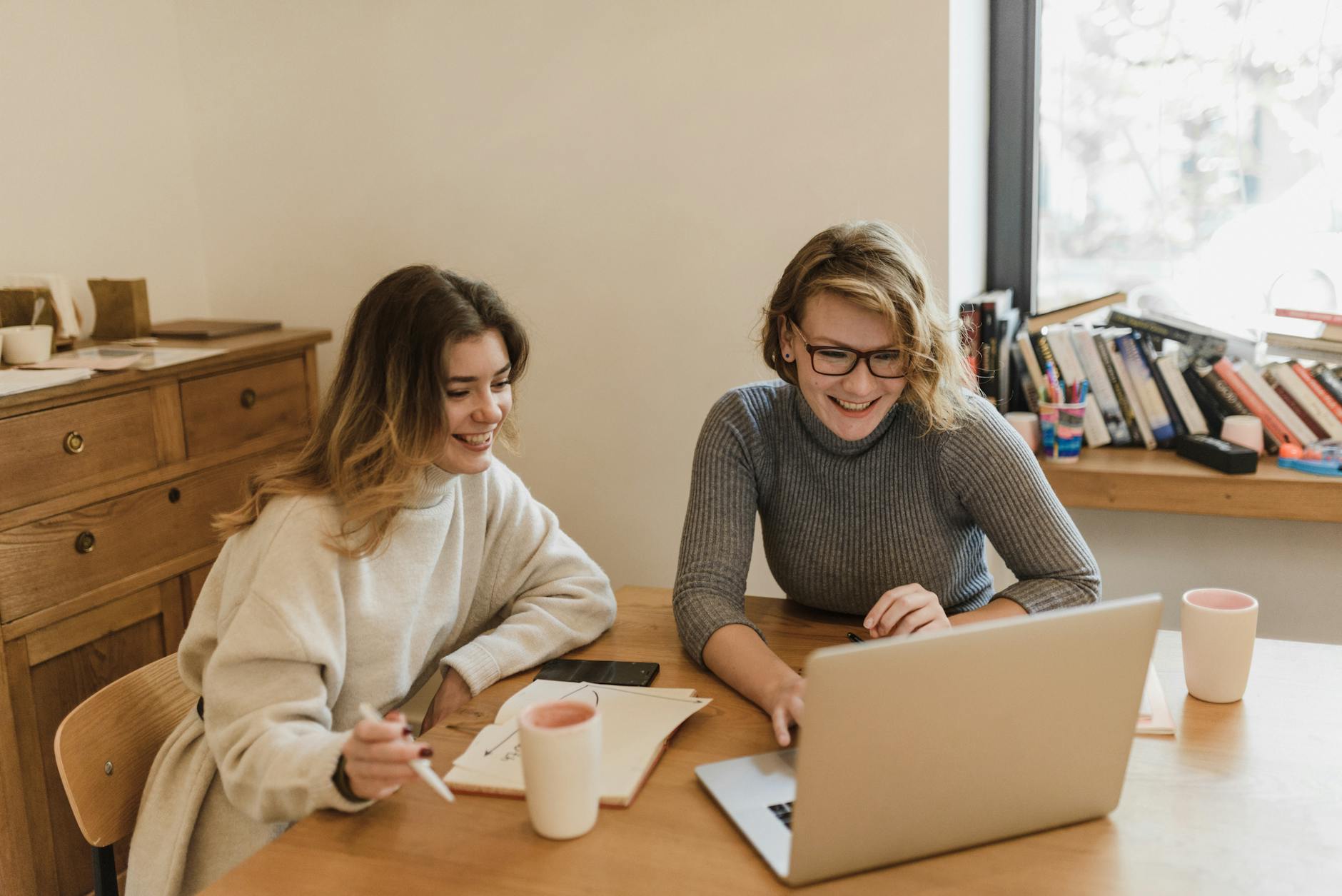 smiling women sitting at desk in office working on laptop