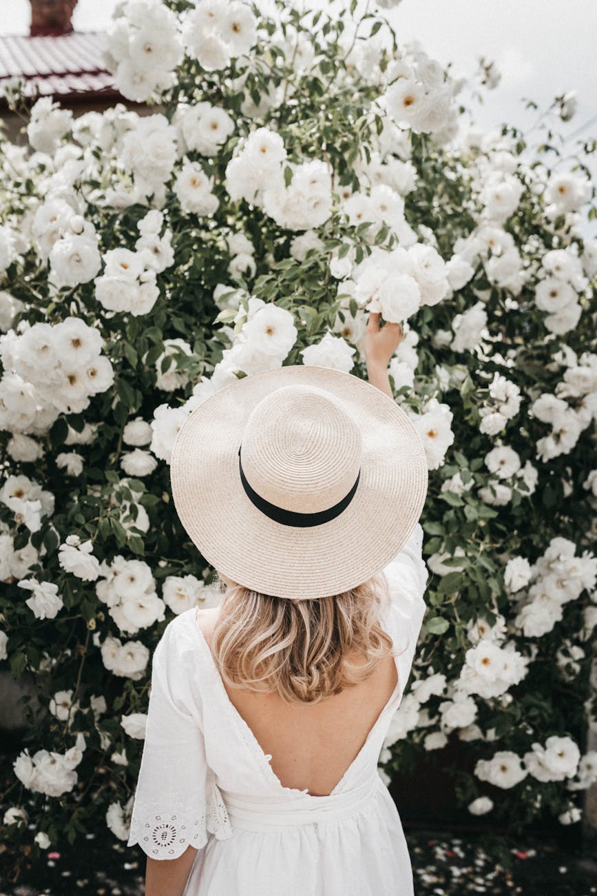 a woman in white dress picking flowers in the garden