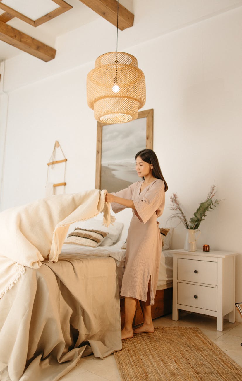 woman in brown dress fixing the bed linen