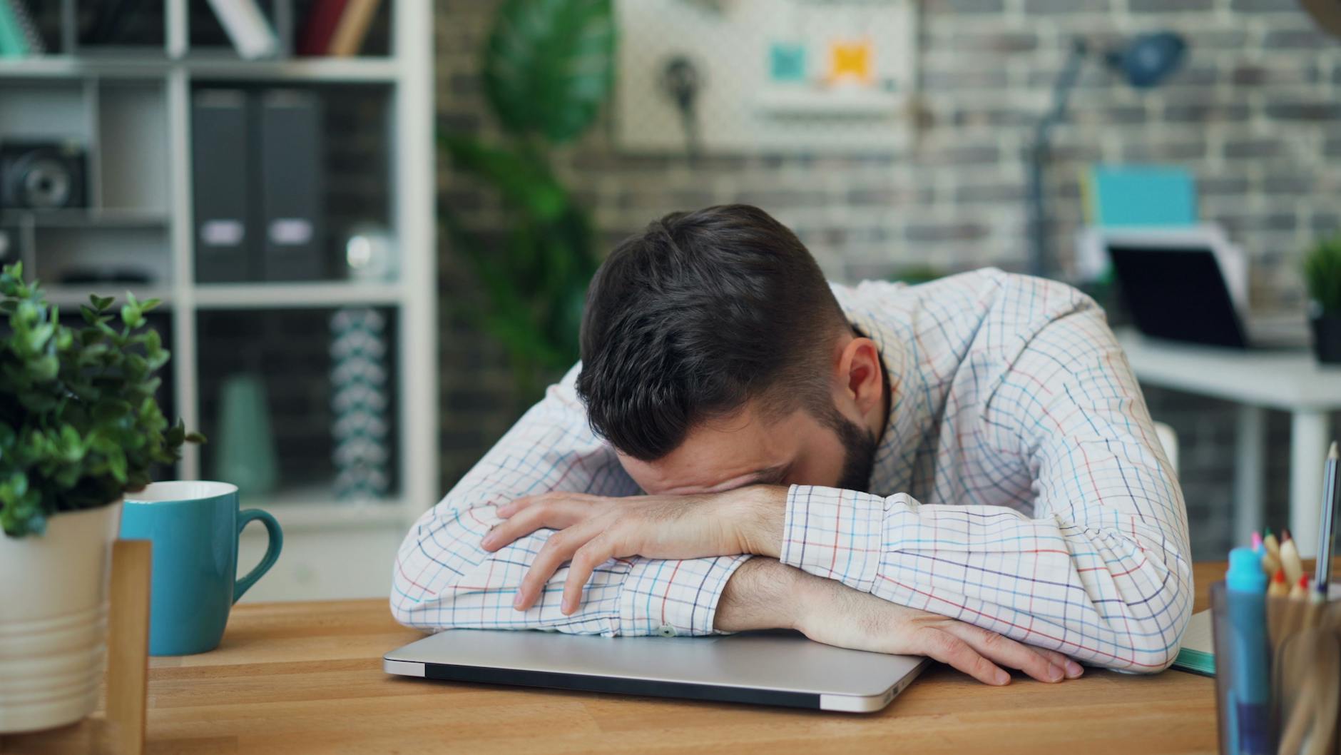 man in shirt lying down on table at office