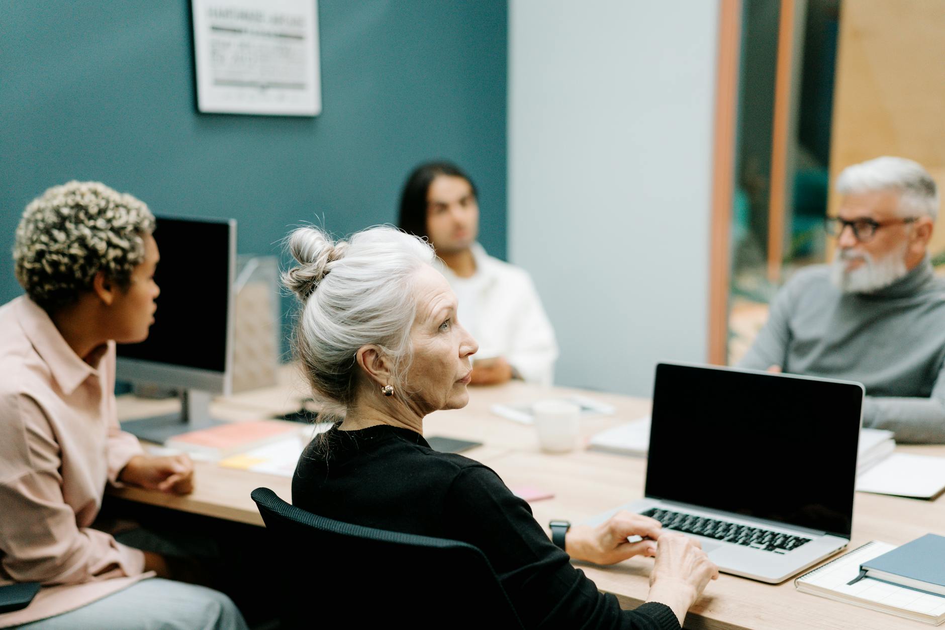 woman in black sweater sitting on chair in front of macbook pro