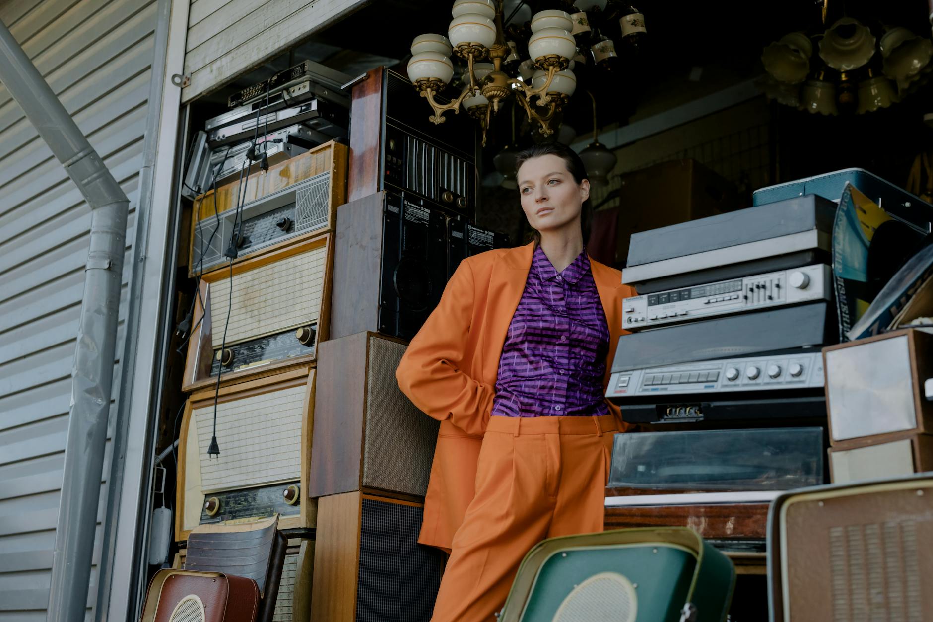a woman in orange blazer standing beside vintage radio