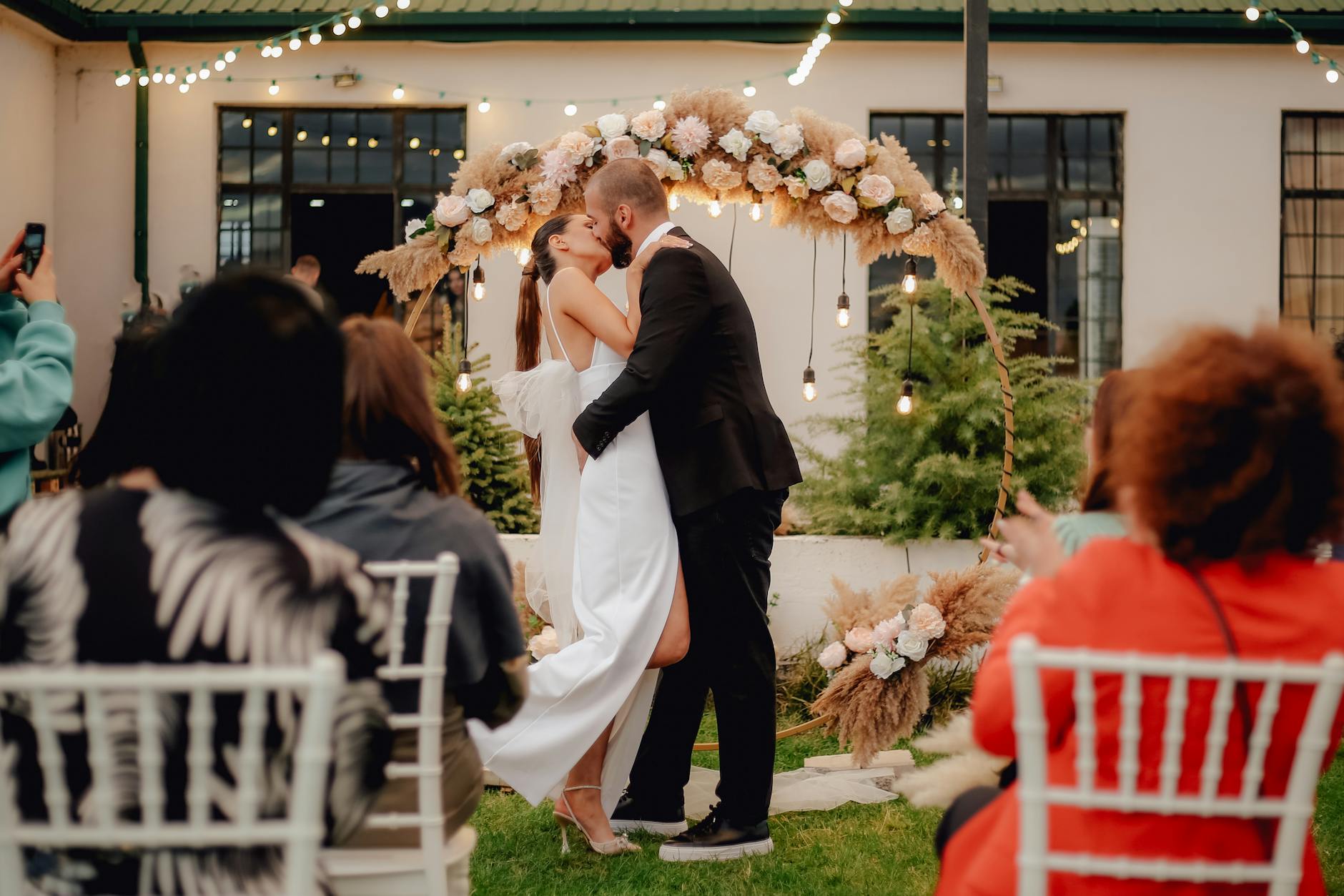 bride and groom kissing near flower arch