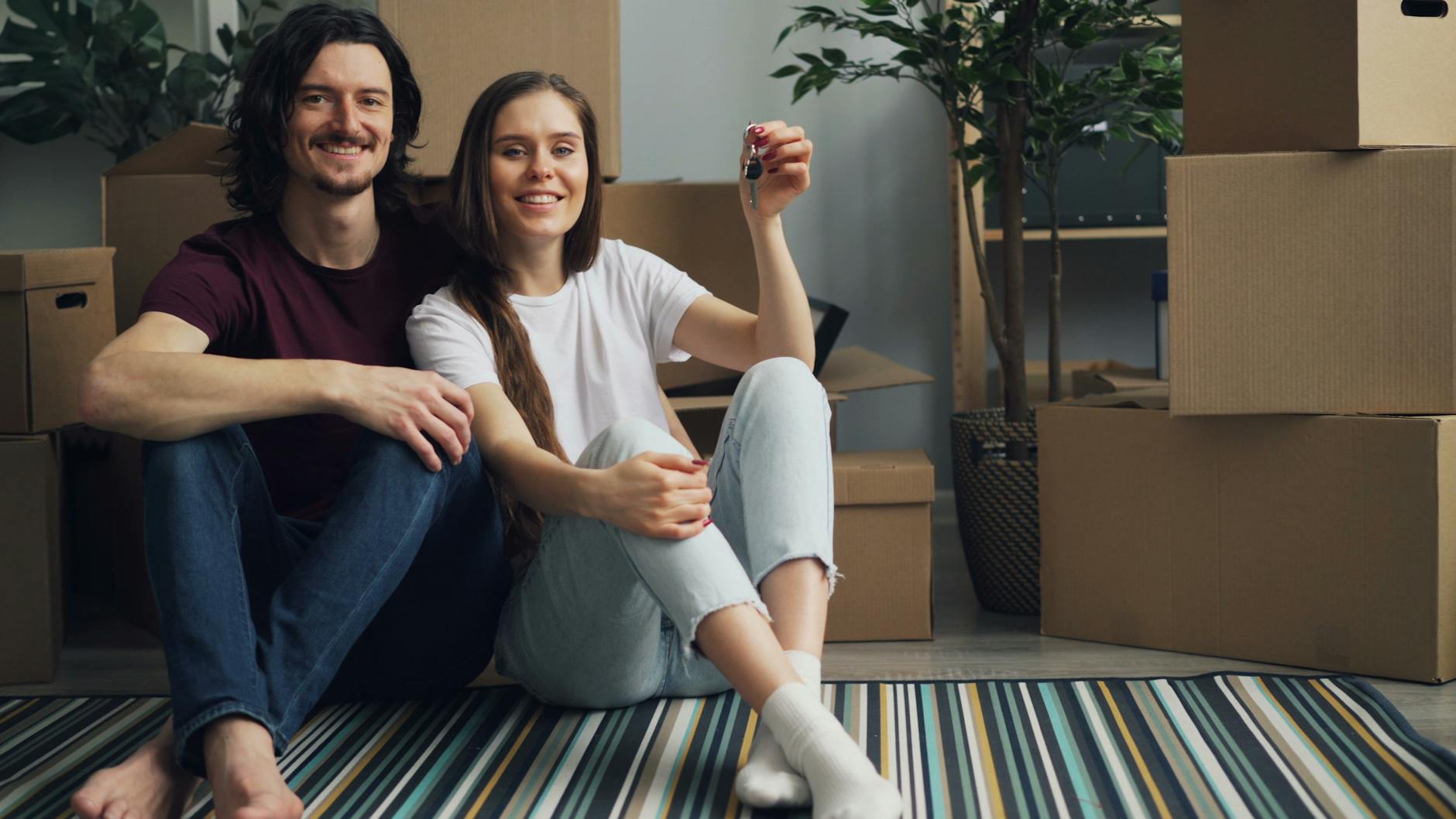 couple sitting with keys on carpet in house