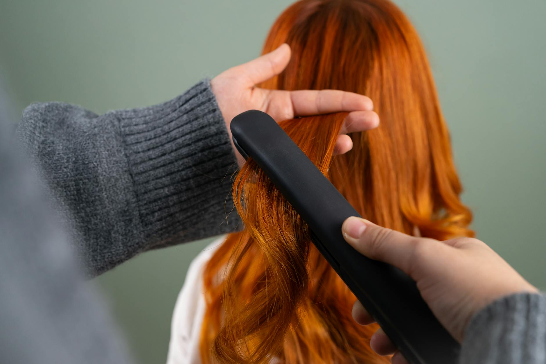 styling long red hair with flat iron indoors