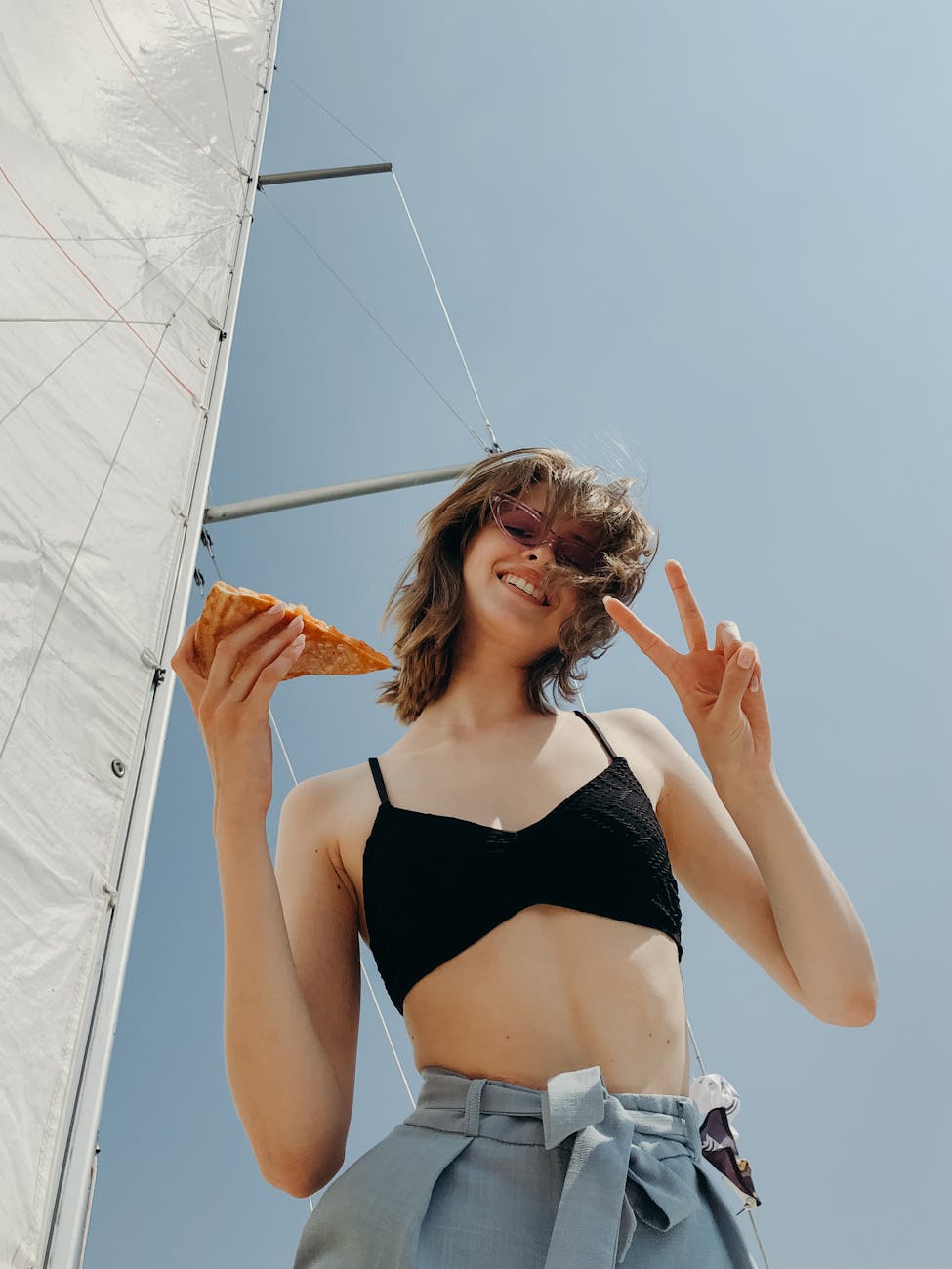 pretty woman in black bikini top holding a slice of pizza