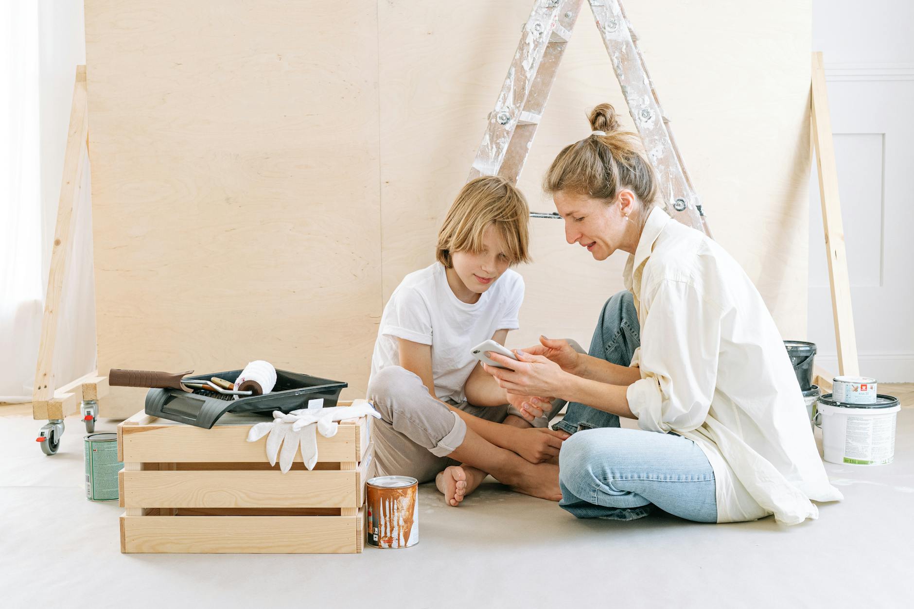 mother and son sitting on floor using cellphone