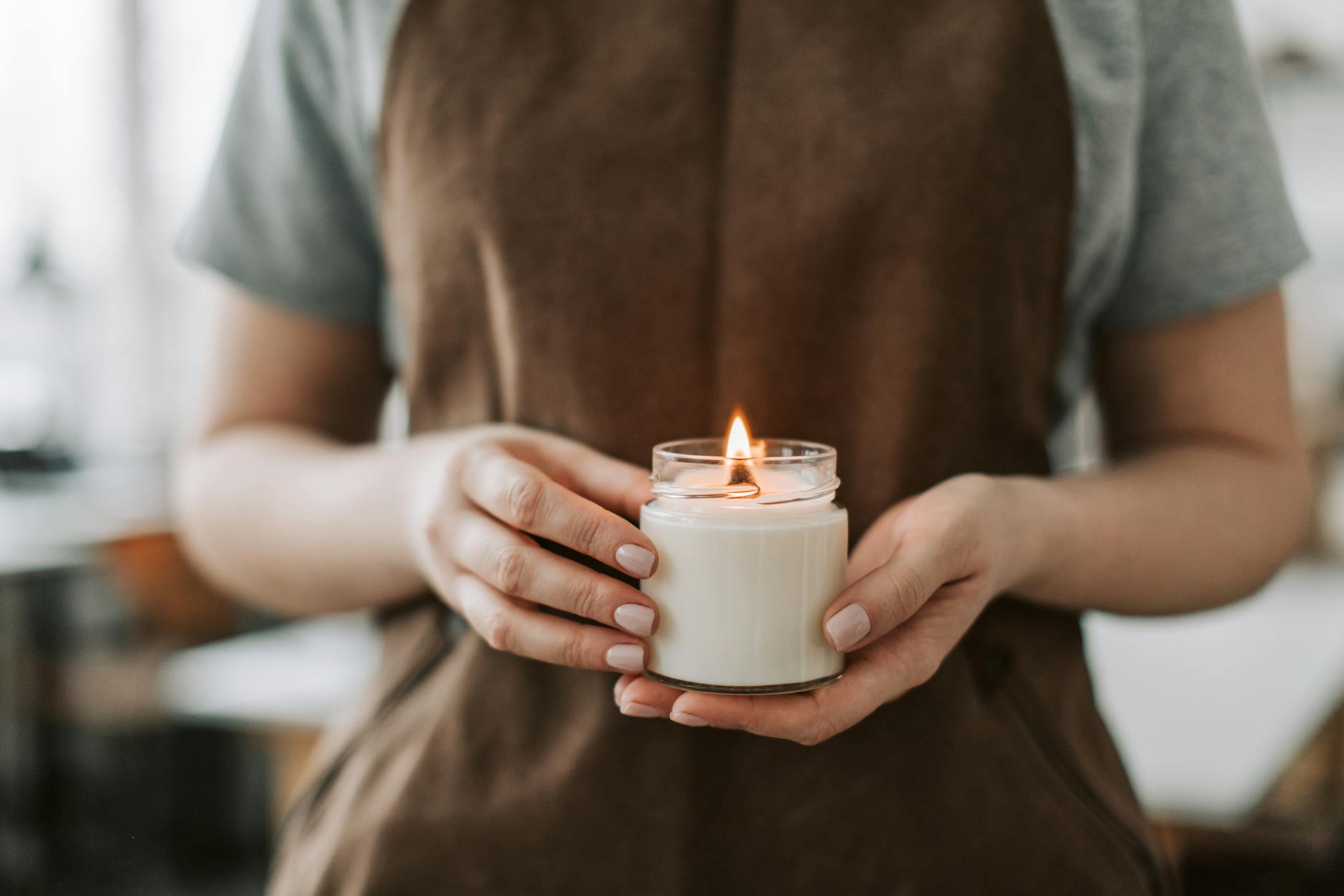 person in brown apron holding candle