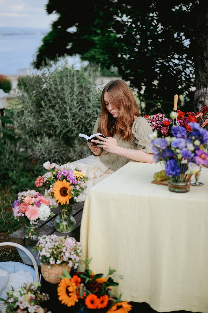 long haired redhead relaxing at a picnic table with a book in hands