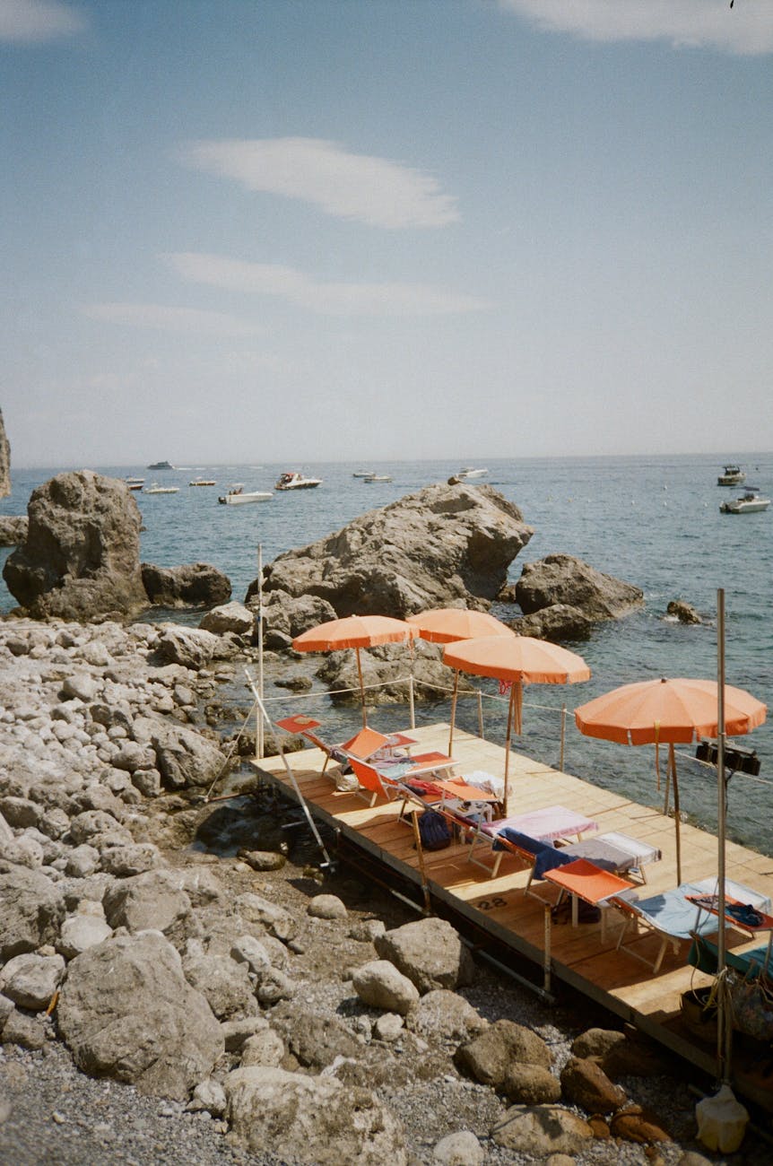beach umbrellas and sunbeds on boardwalk on seashore in italy
