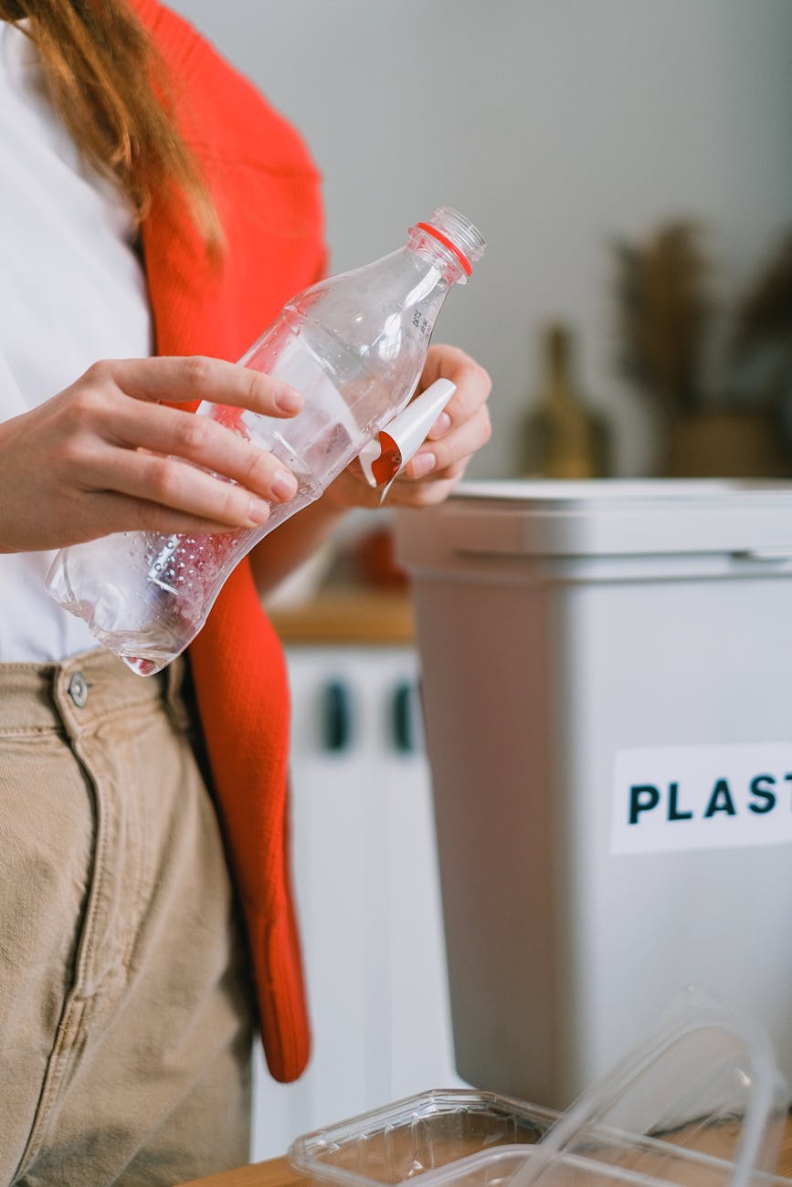 person removing a label from a plastic bottle