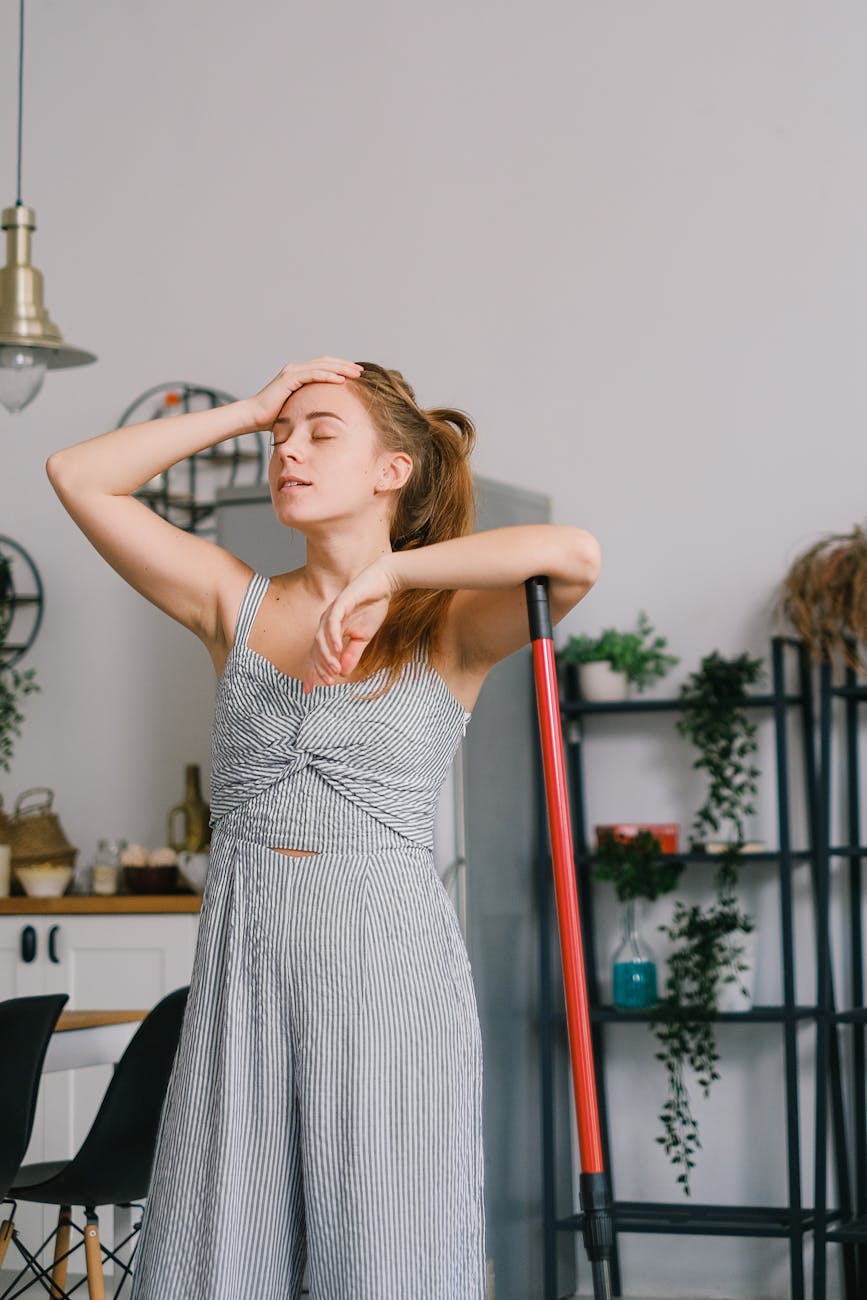 tired housewife touching head during housework in room