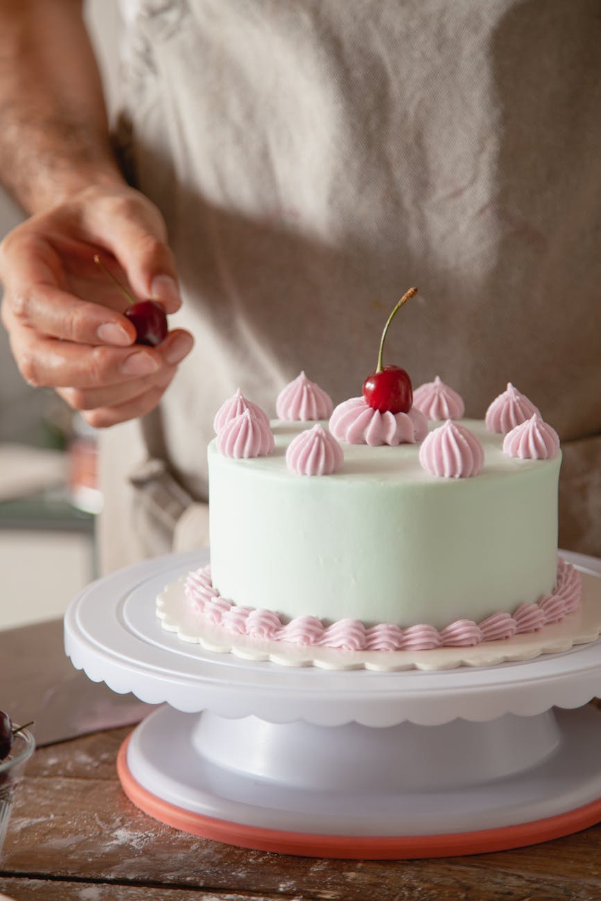 baker putting fresh cherries on a cake