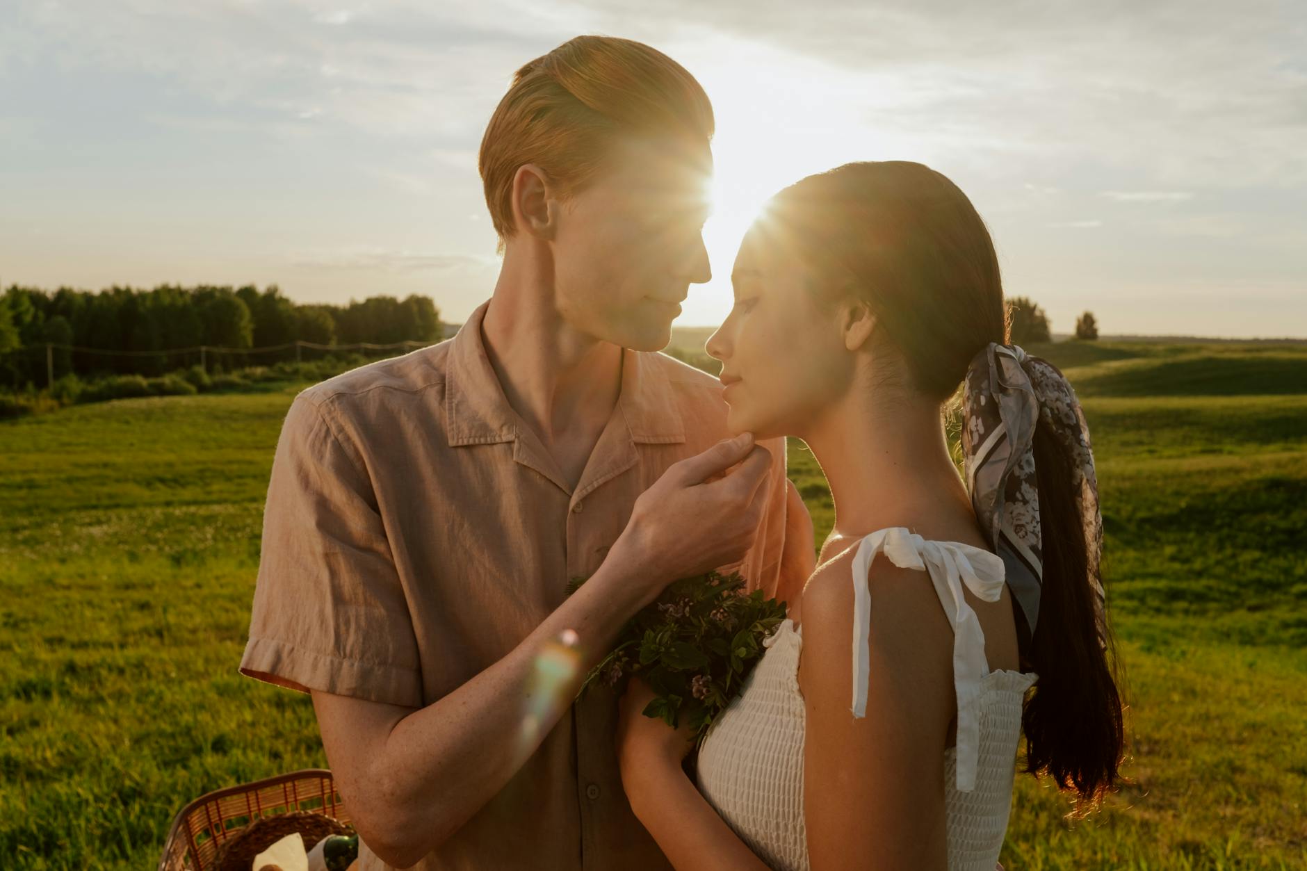 man and woman cuddling on a meadow
