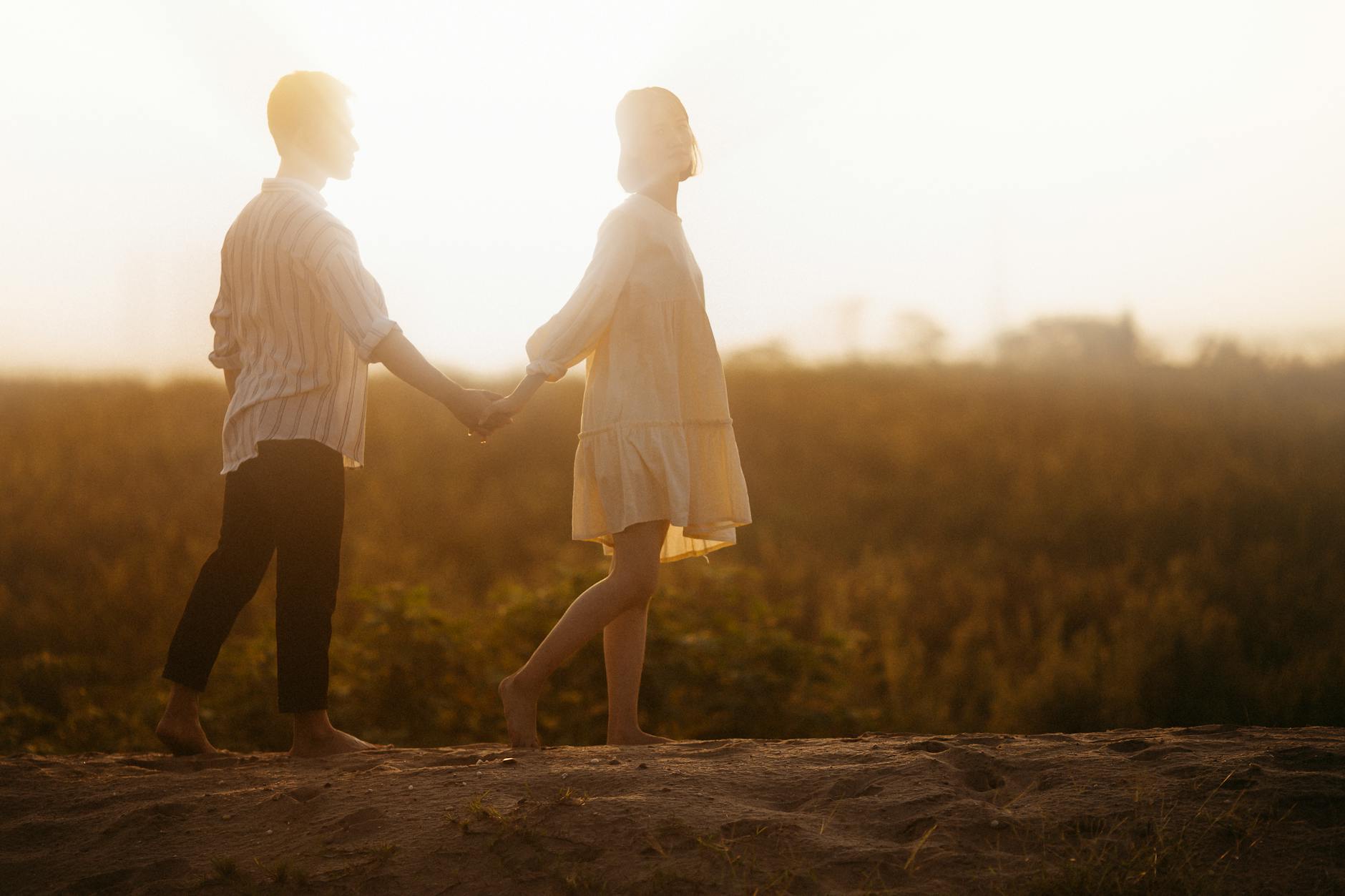 couple holding hands on sand field