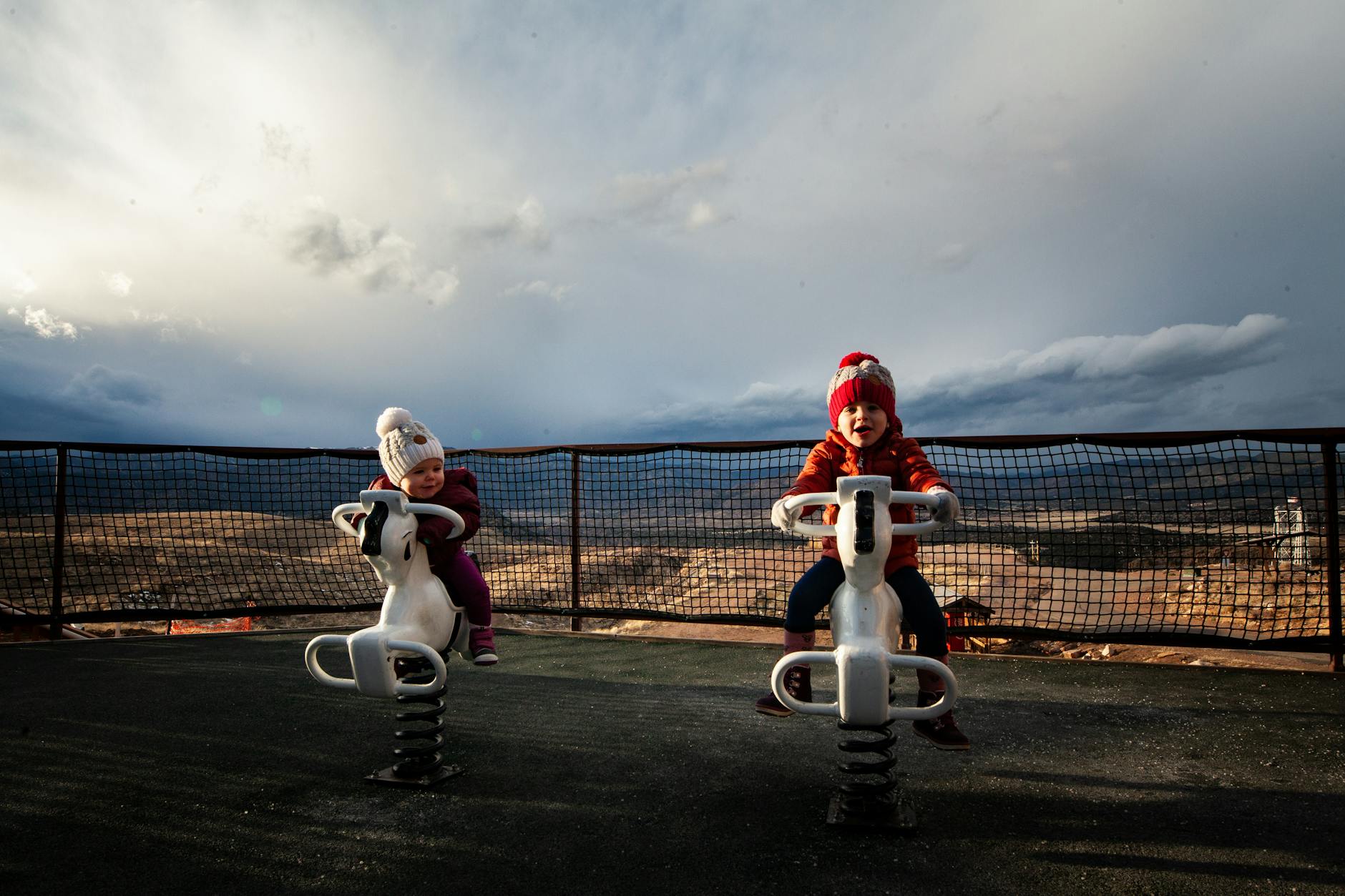 photo of toddlers riding on spring horses