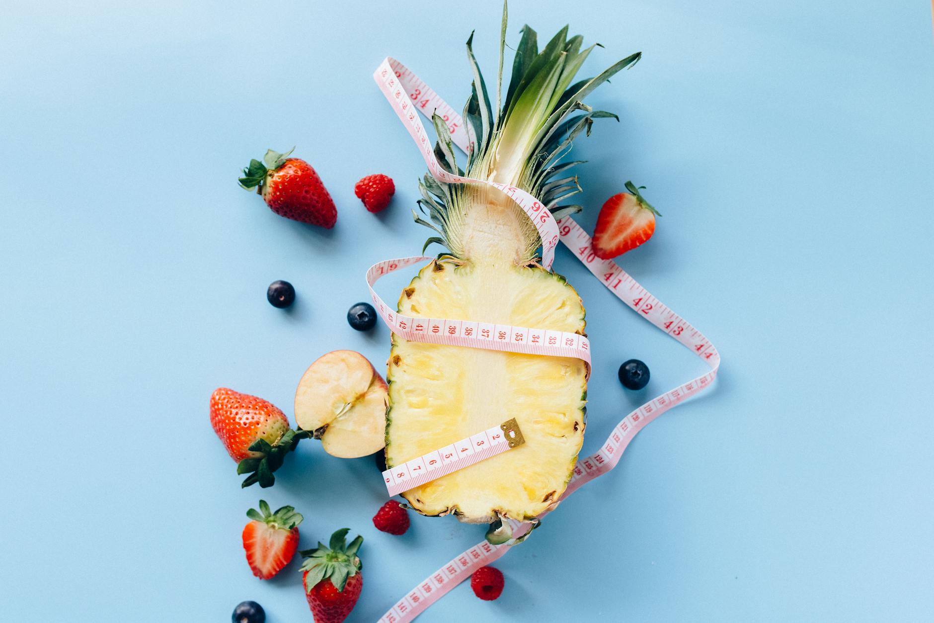 healthy fruits and a tape measure on a blue surface