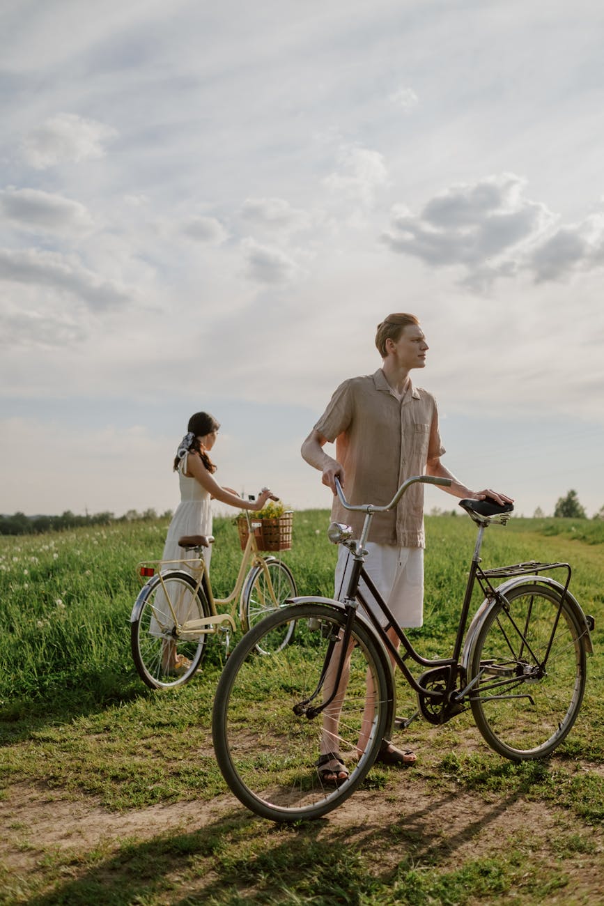 man and woman standing beside bicycle on green grass field