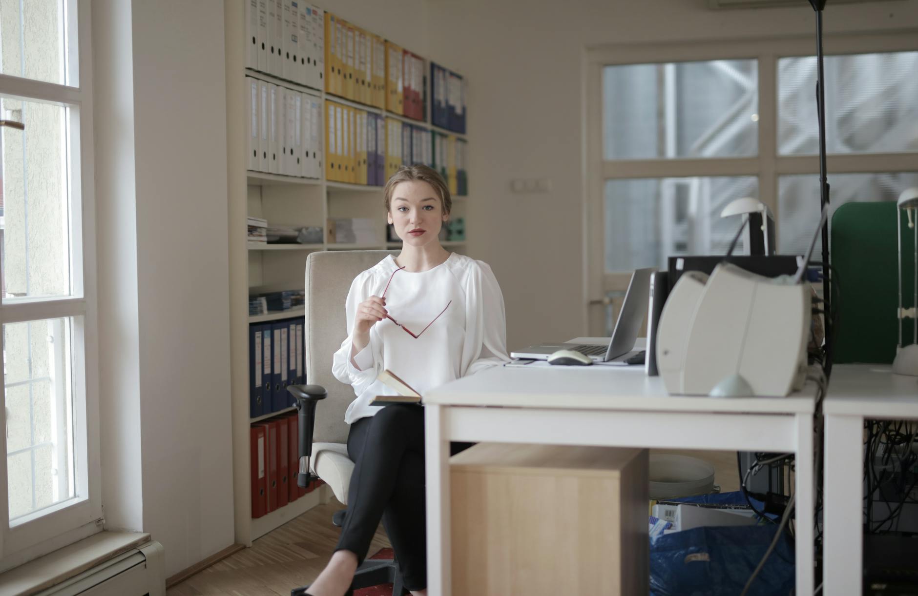 woman in white long sleeve shirt sitting near window pane