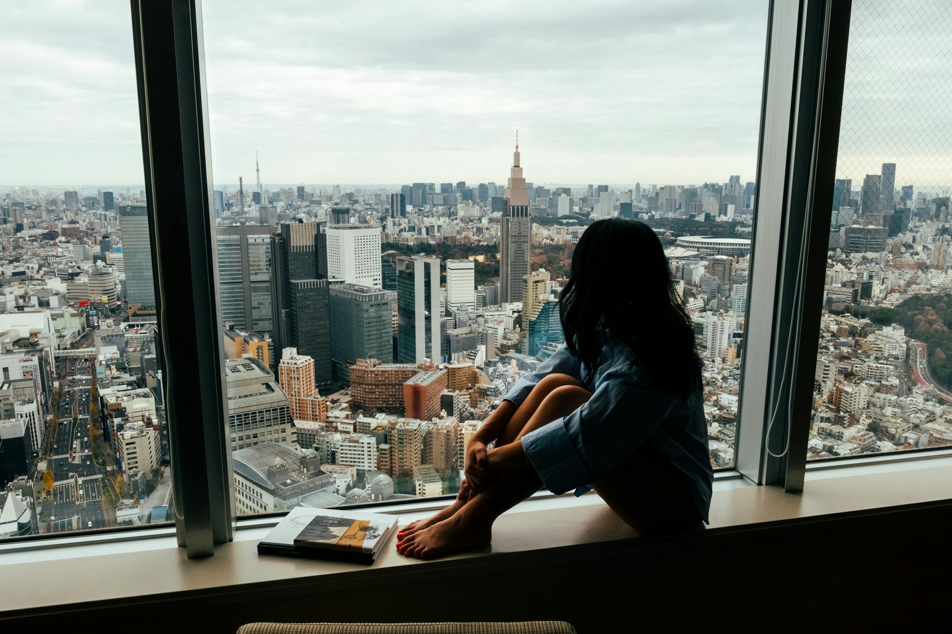 woman sitting by window with tokyo cityscape view