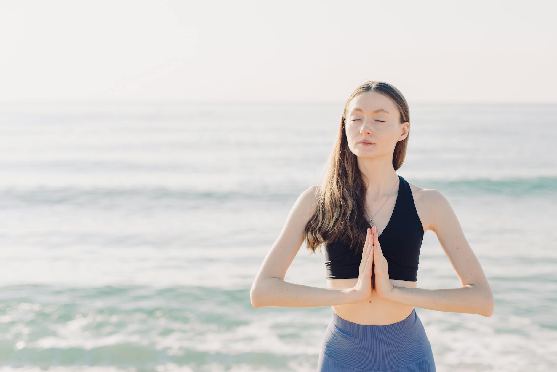 woman meditating near body of water