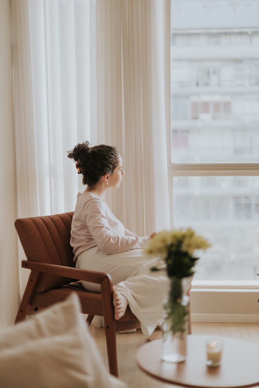 woman gazing out from cozy indoor setting