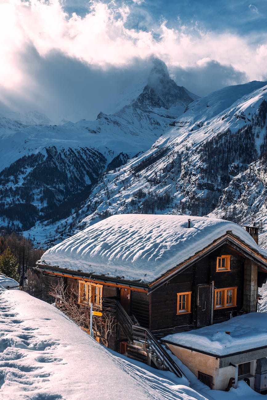 wooden house with snow on roof in winter mountainous terrain