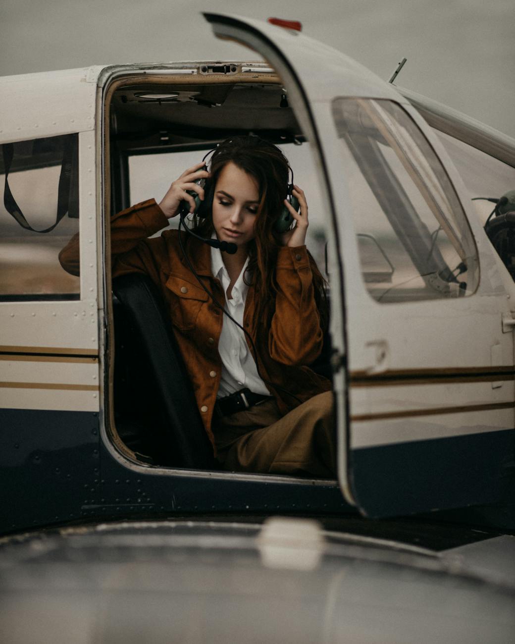 stylish woman in headset sitting in plane