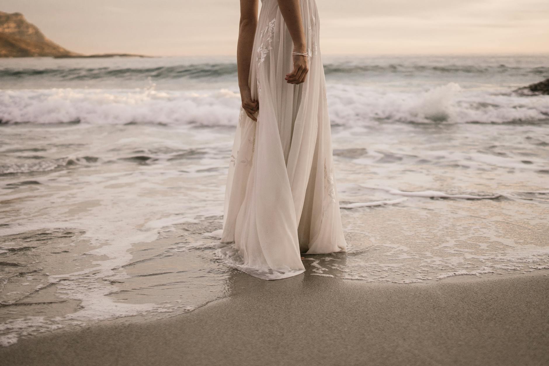 woman in white long dress standing on beach