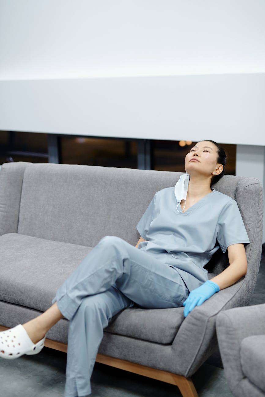 a woman in gray scrub suit resting on the sofa