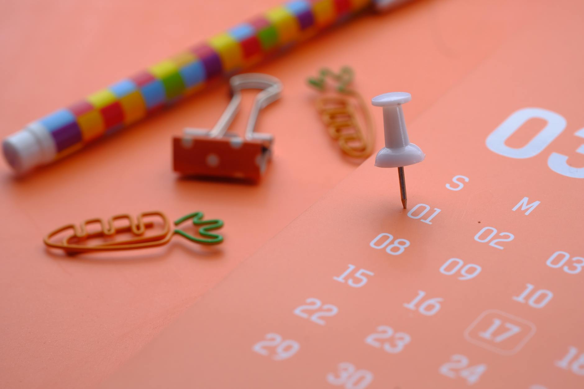 white push pin on orange calendar paper