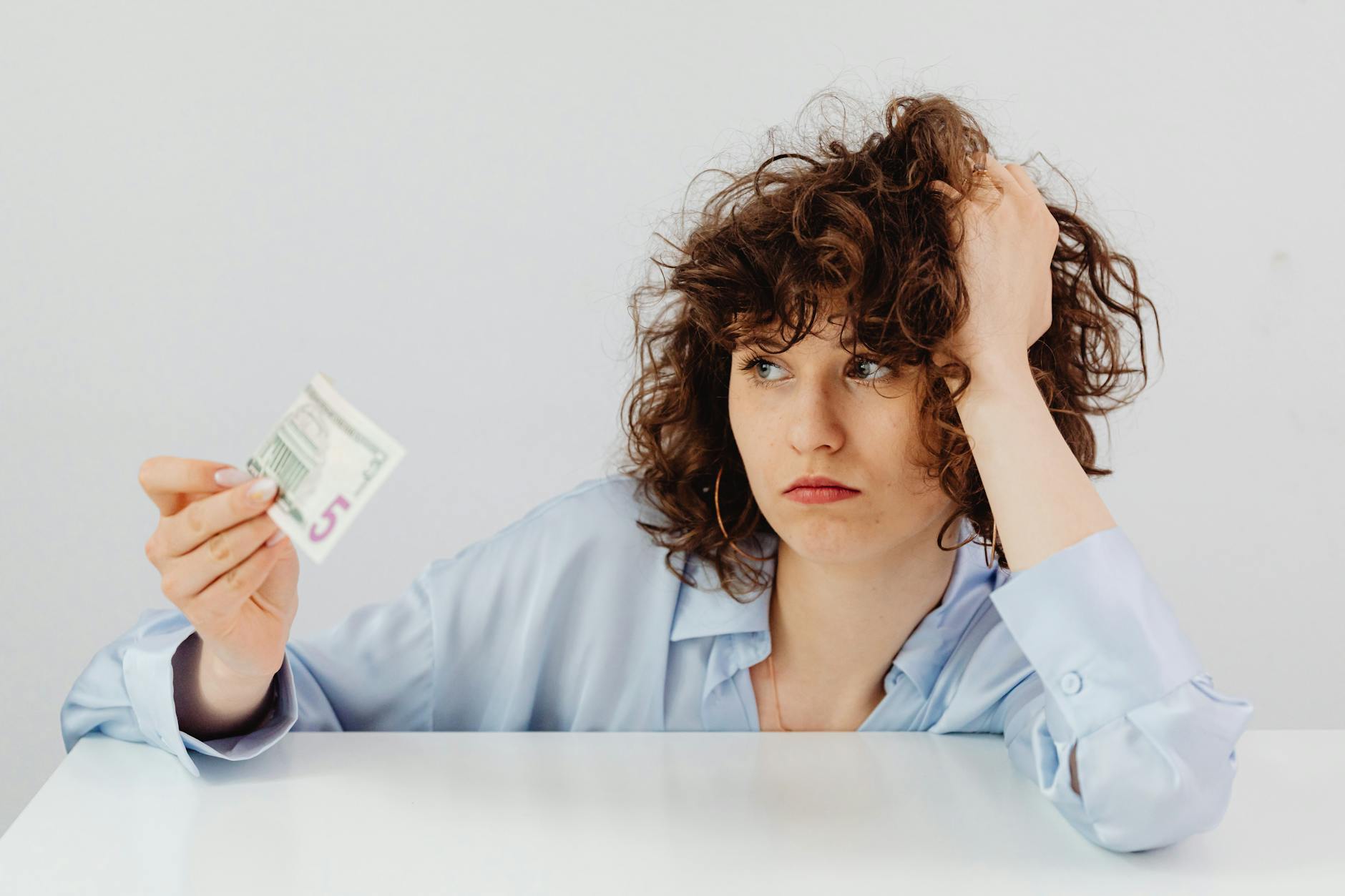 curly haired woman holding a paper money