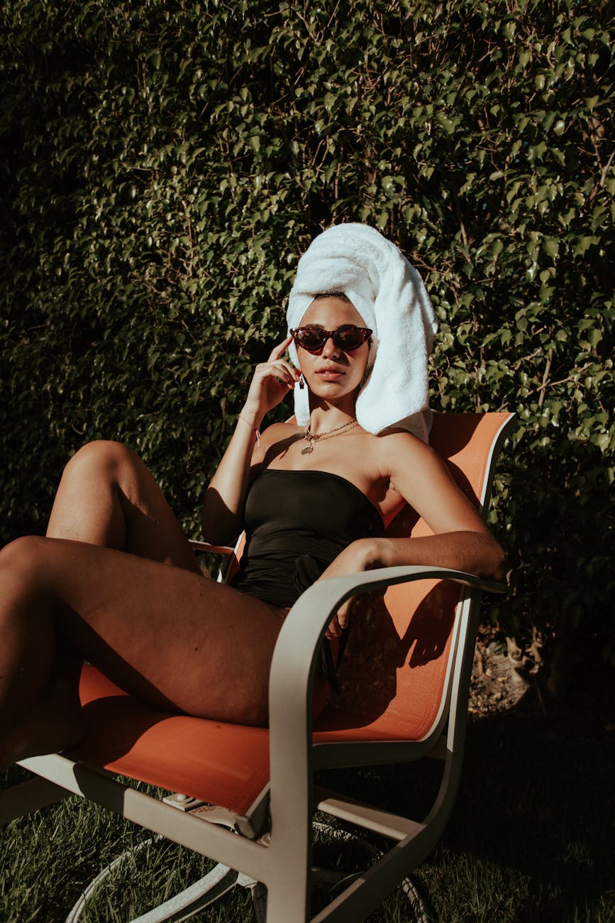 woman in black tube top sitting on a chair with her hair wrapped with towel
