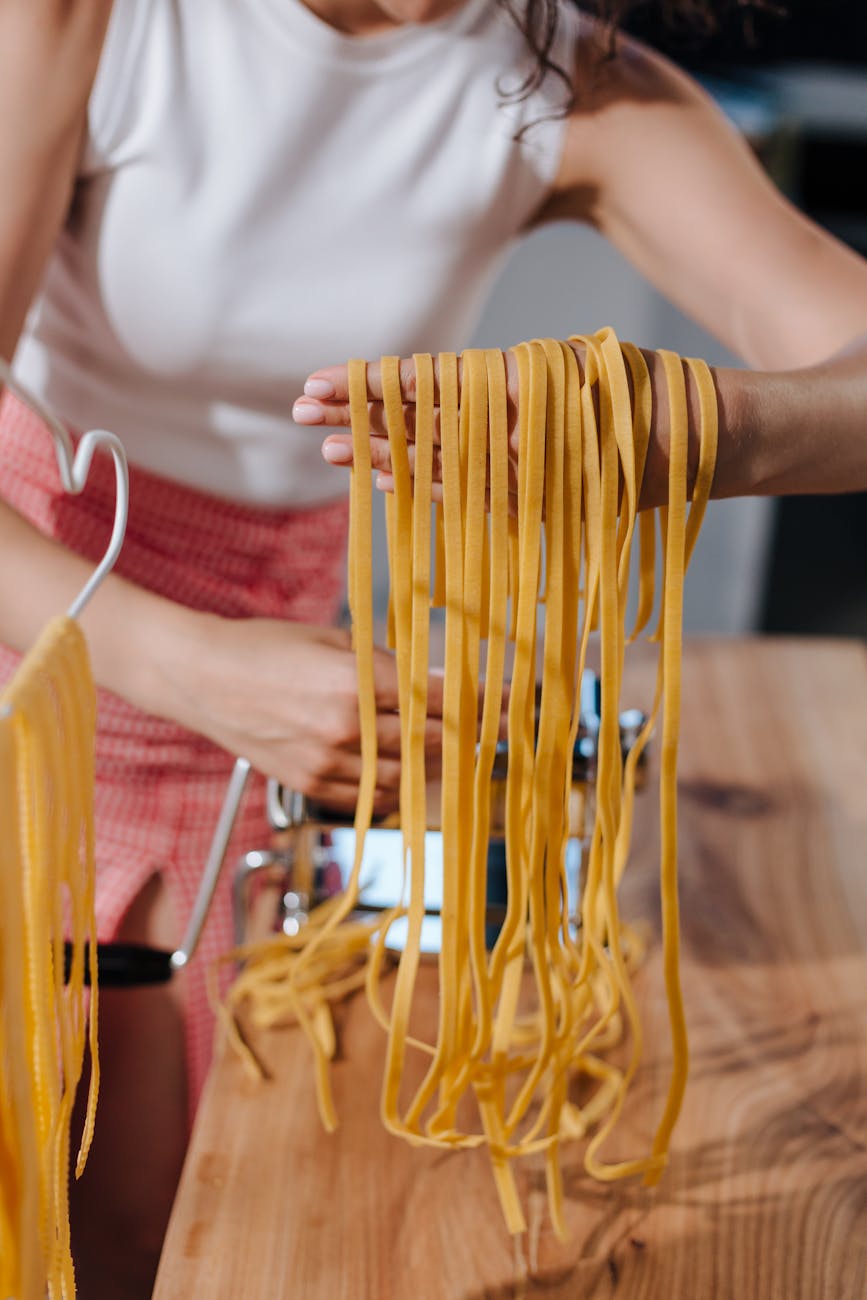 a female taking pasta from pasta maker and putting it on her hand