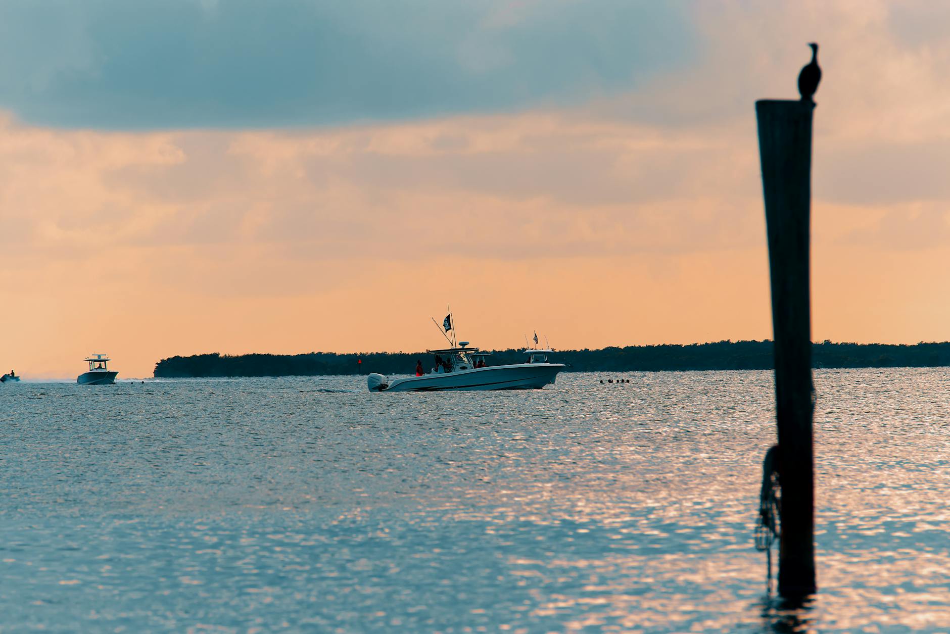 a boat sailing in the ocean during sunset