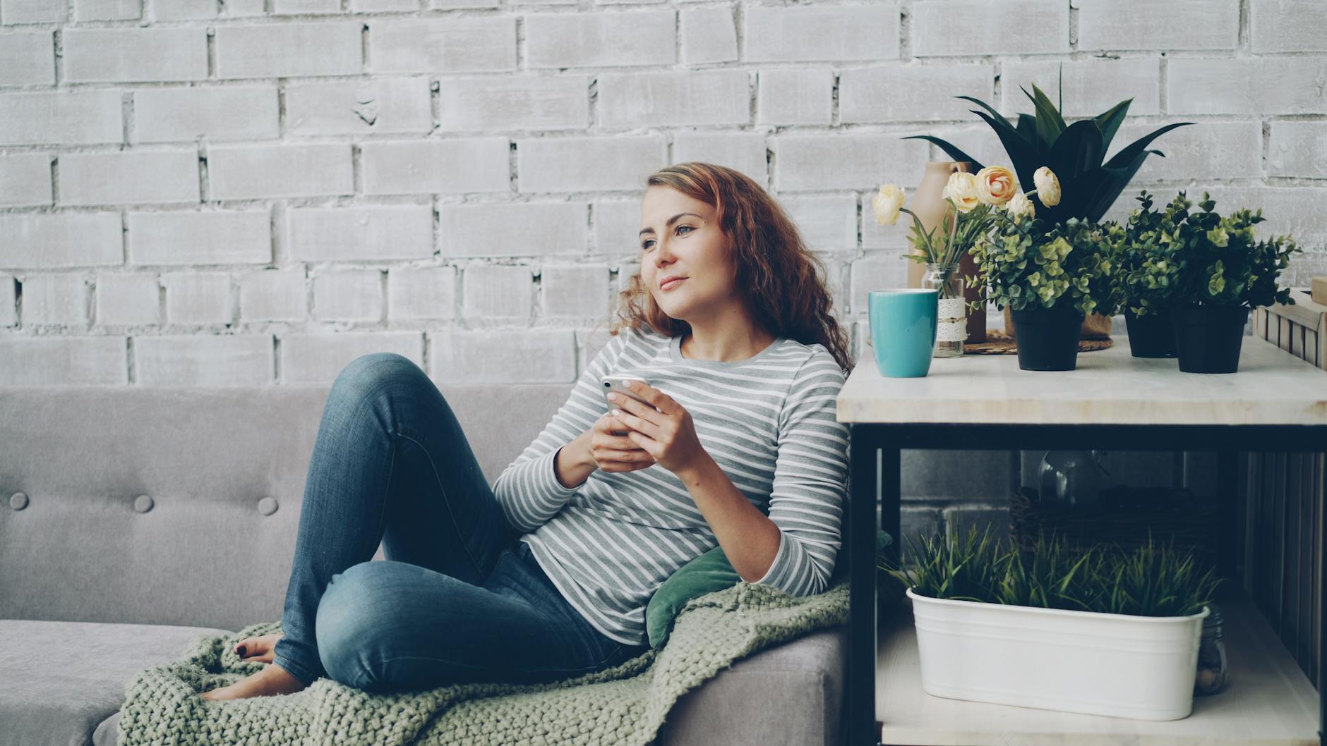 woman relaxing on couch with plants indoors