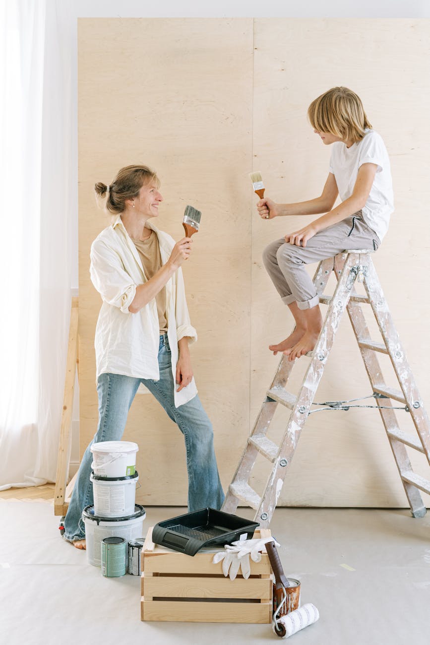 a woman and a boy holding paintbrushes