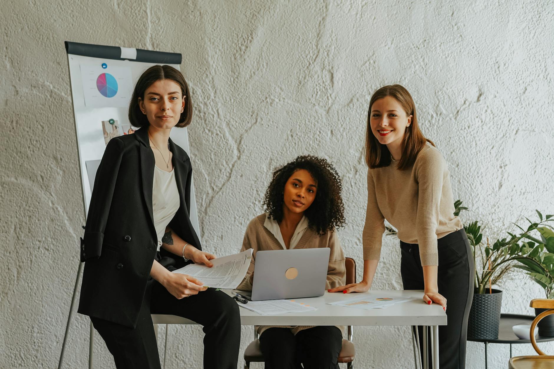 three women around a white table in an office