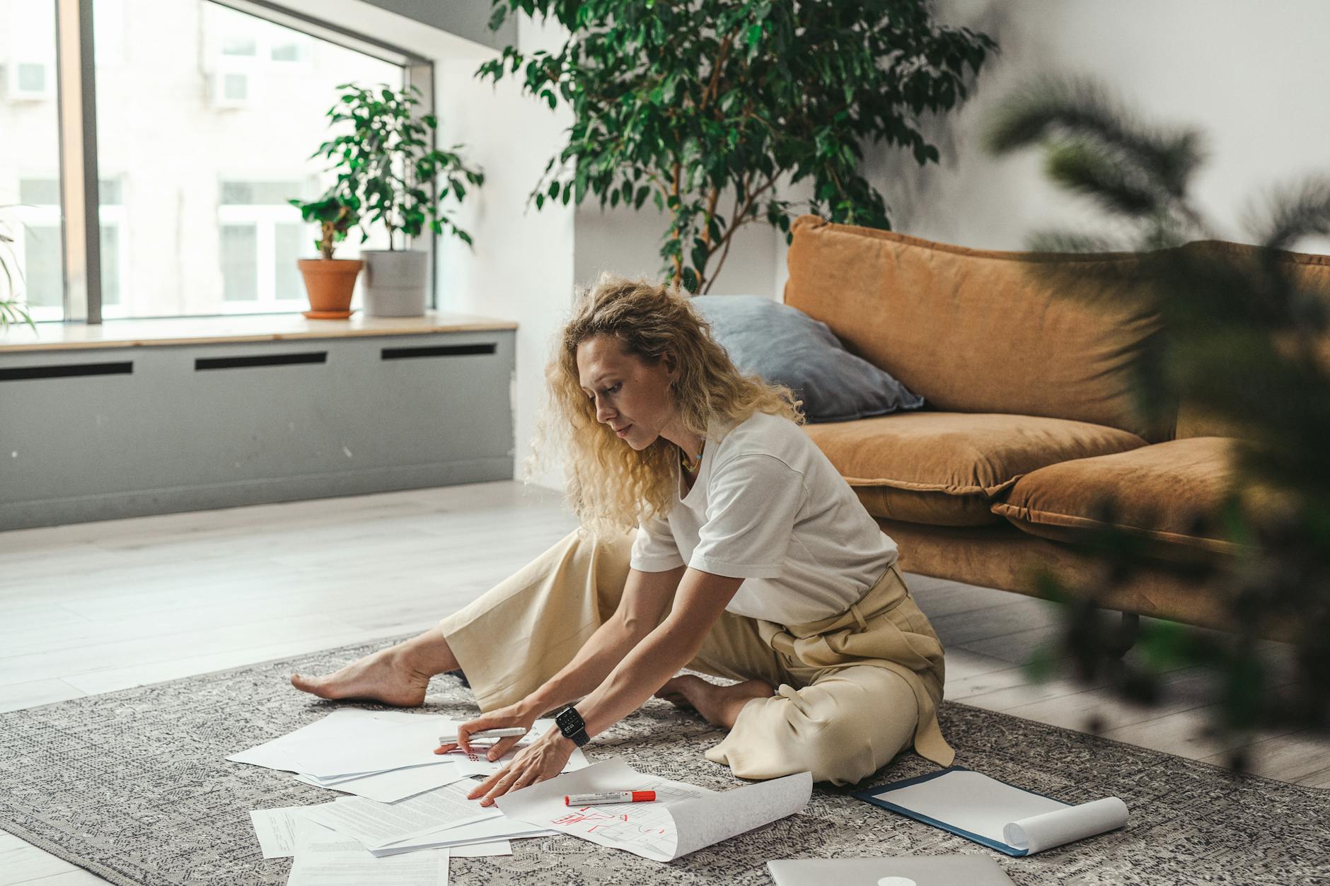 a woman sitting on the floor carpet working with documents