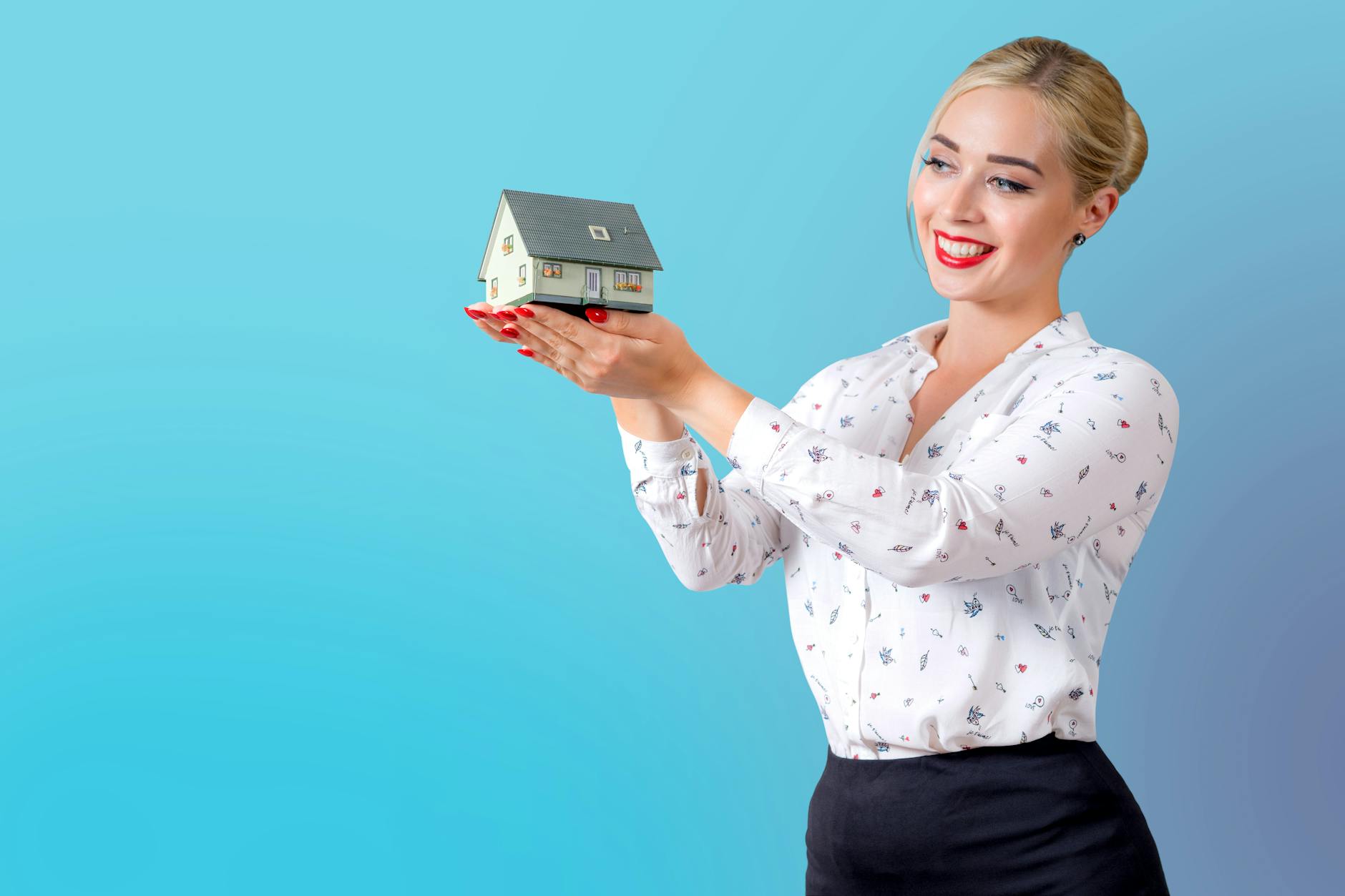 woman in white printed long sleeve shirt holding a model house