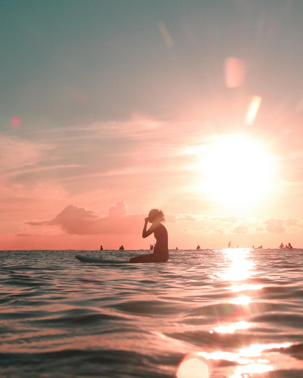 silhouette of a woman sitting on her surfboard