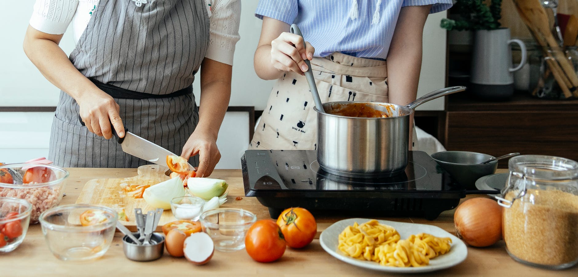 crop women cooking at stove in kitchen