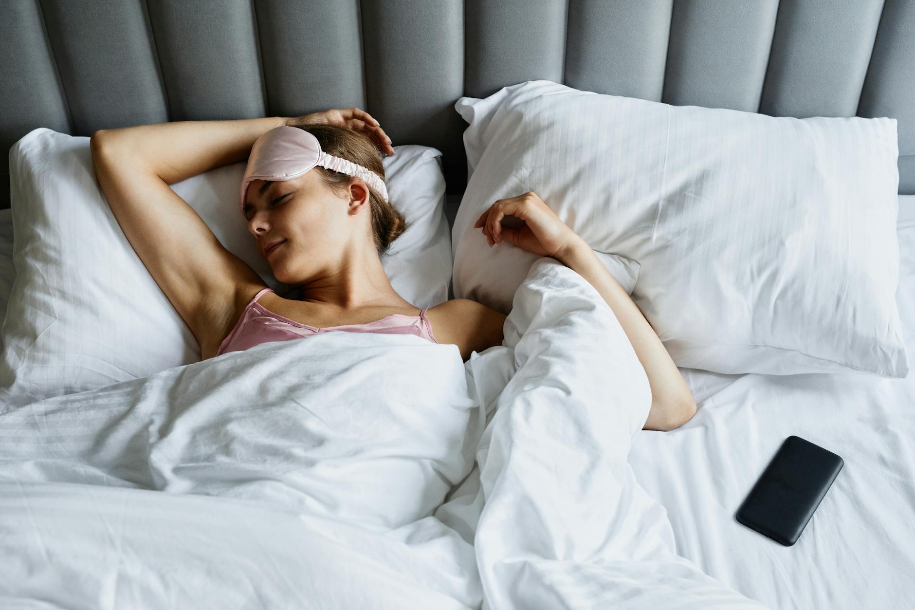 a woman with eye mask sleeping in the bed