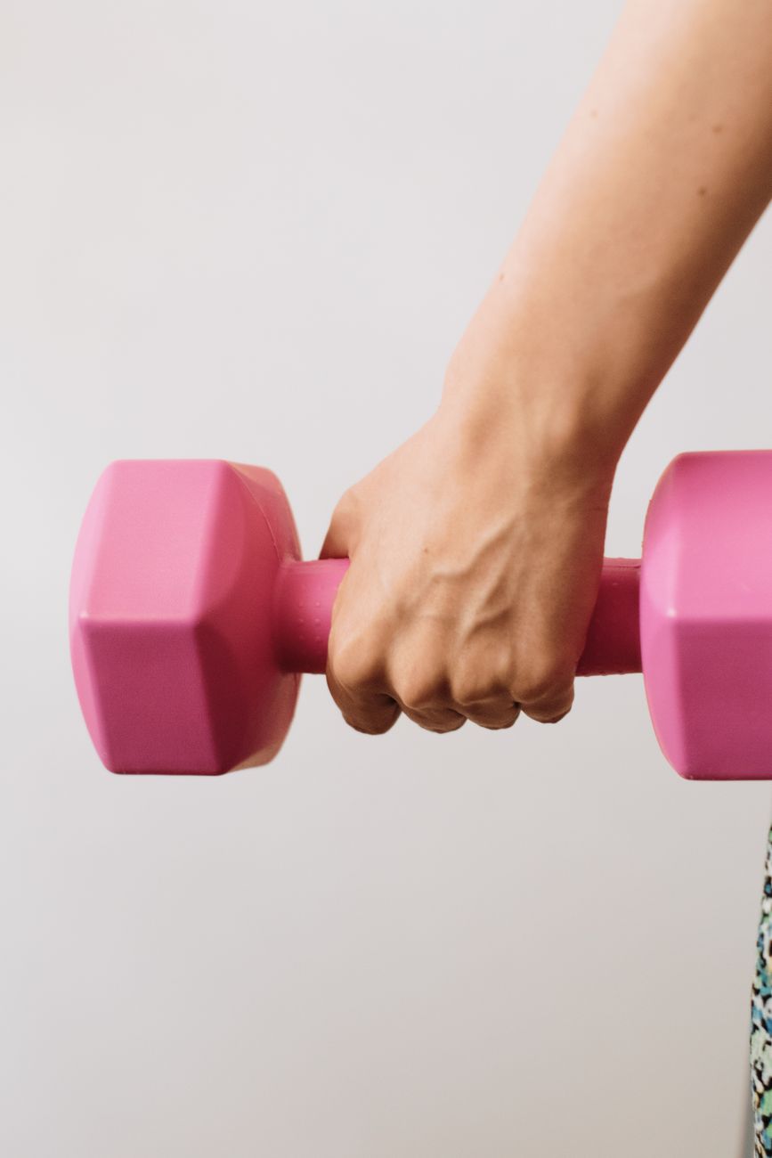 a woman holding a pink dumbbell in her hand