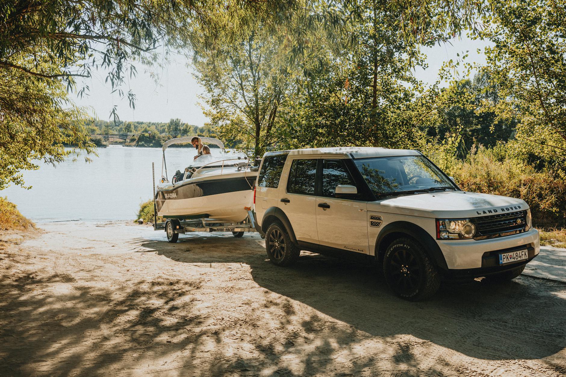 a white suv parked next to a boat