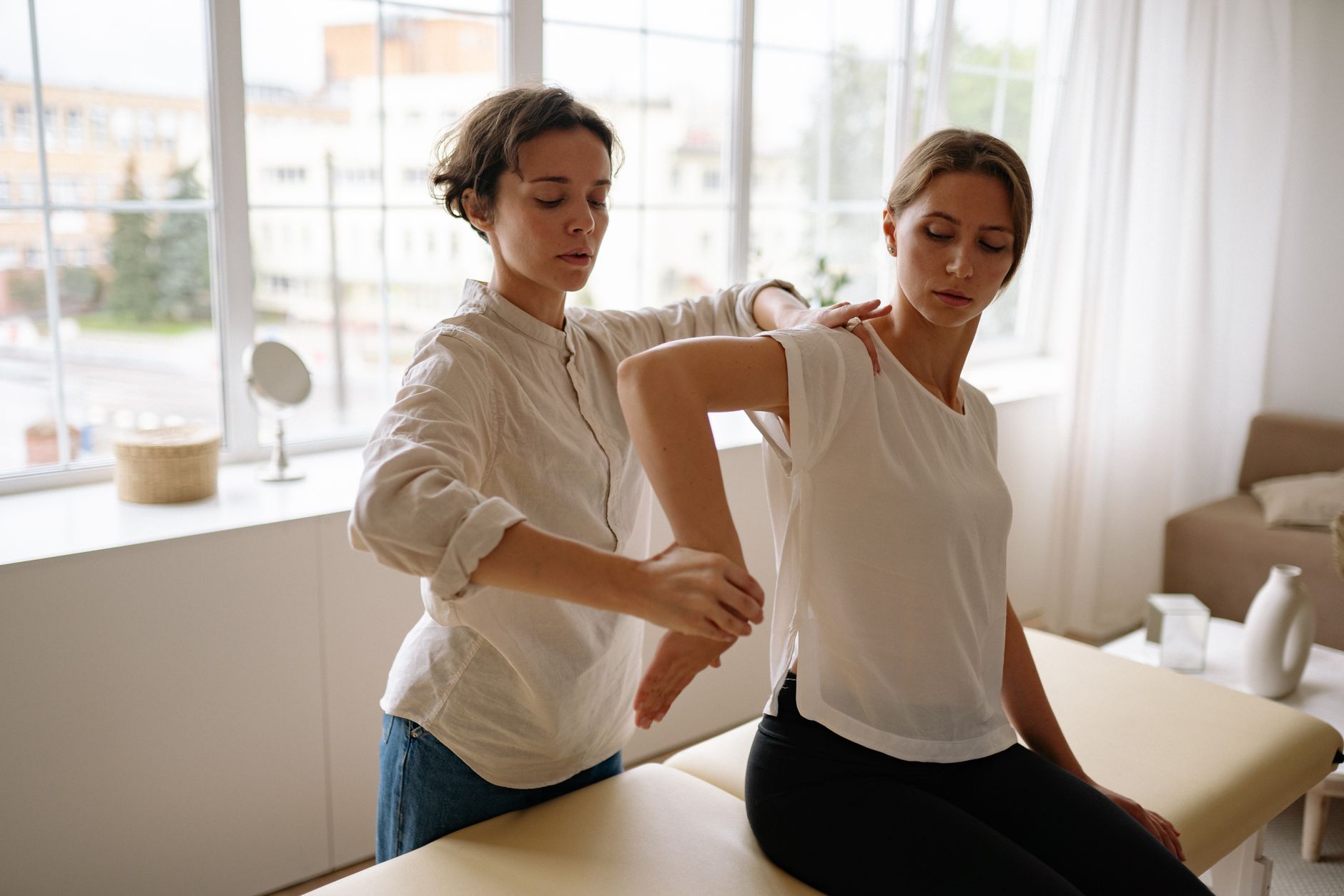 woman in white long sleeve shirt stretching woman s arm