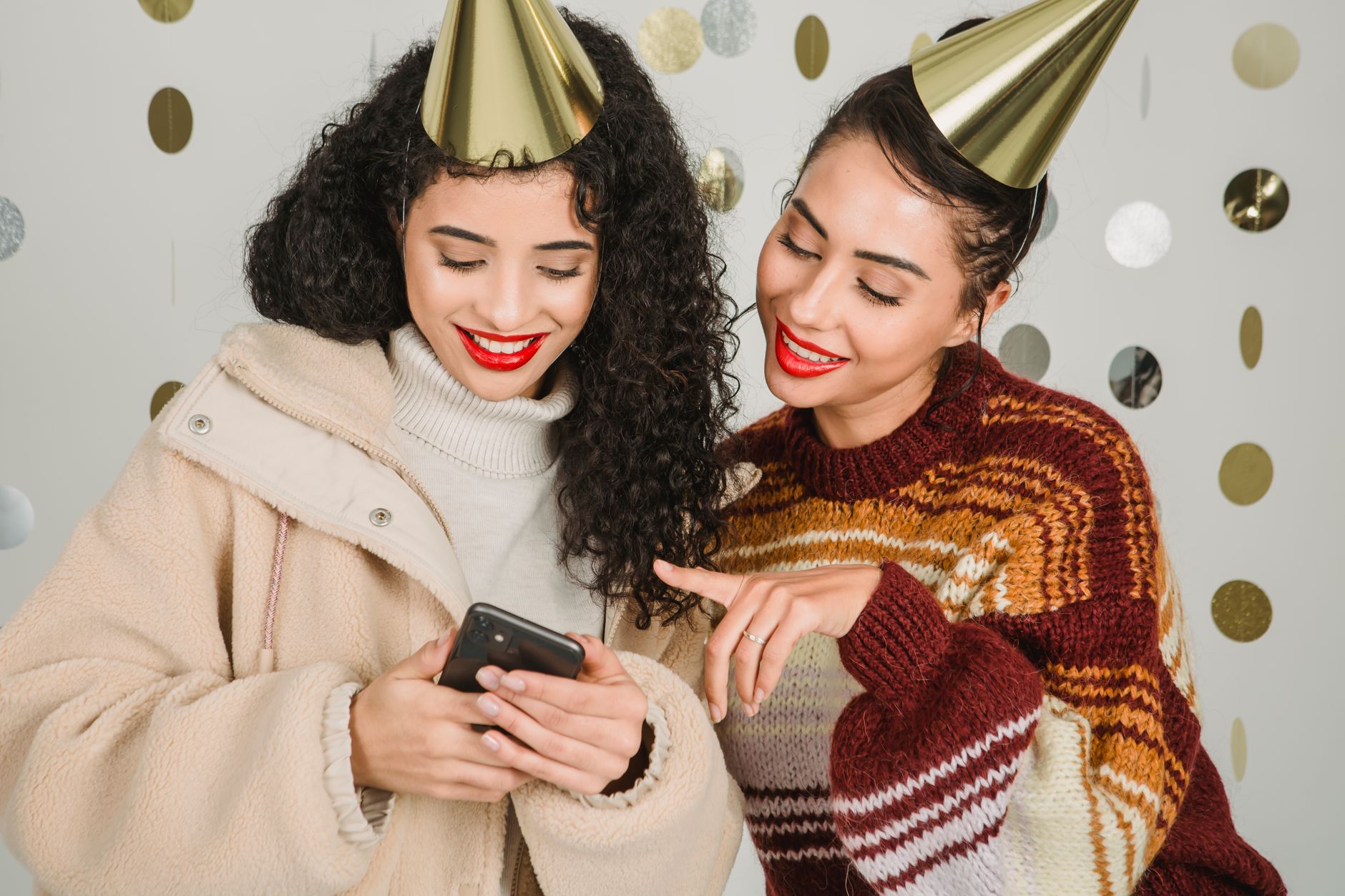 cheerful women browsing smartphone while celebrating holiday