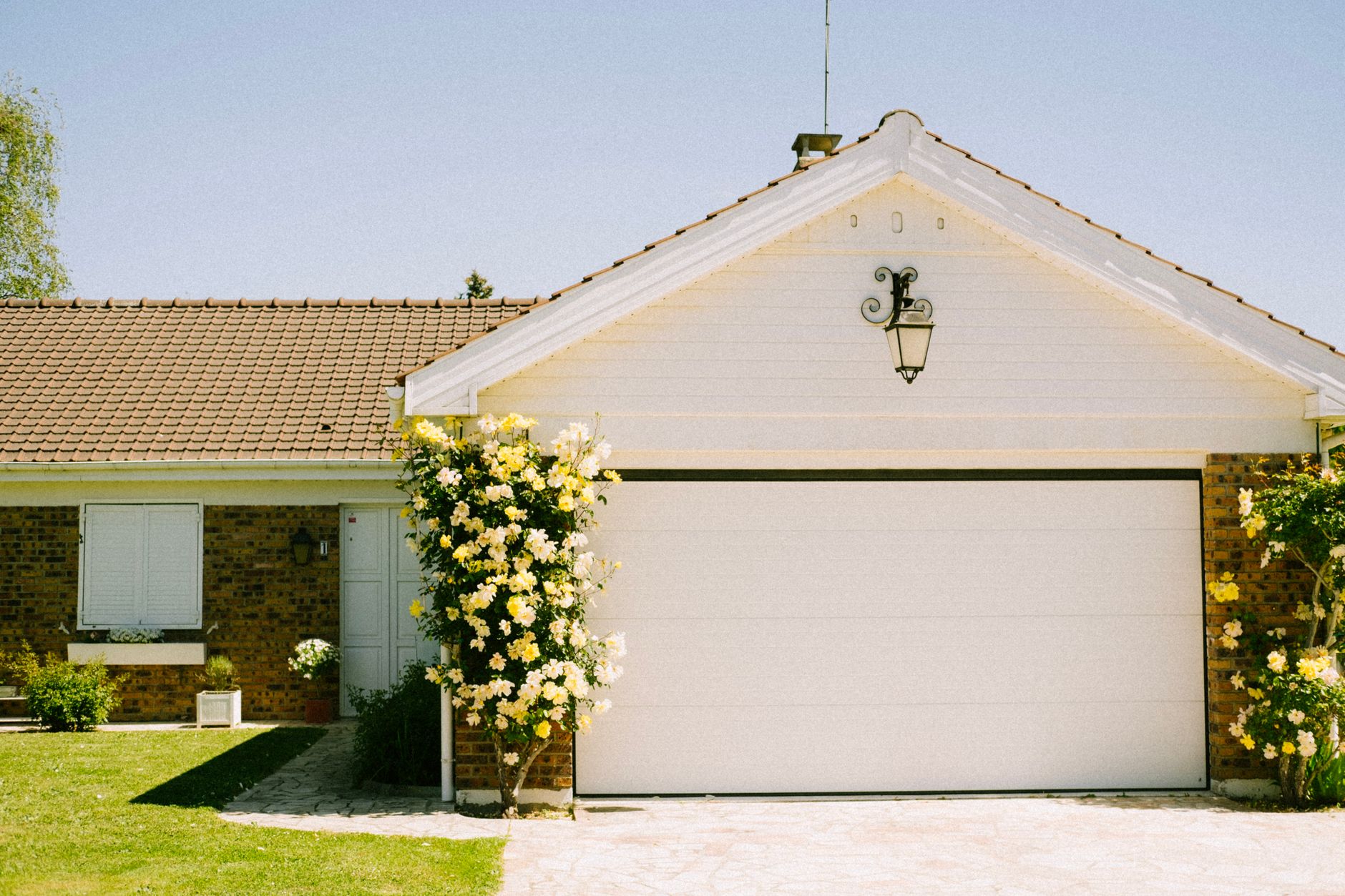 garage driveway with flowering plants on side
