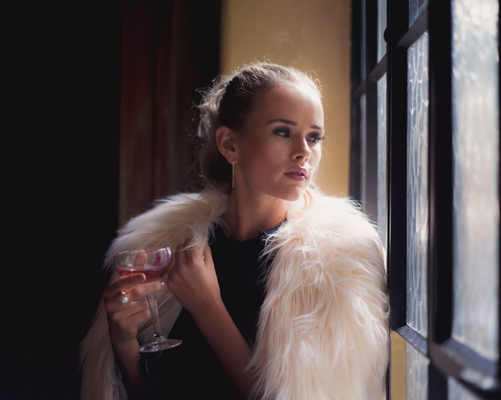 a woman in a fur coat looking out the window