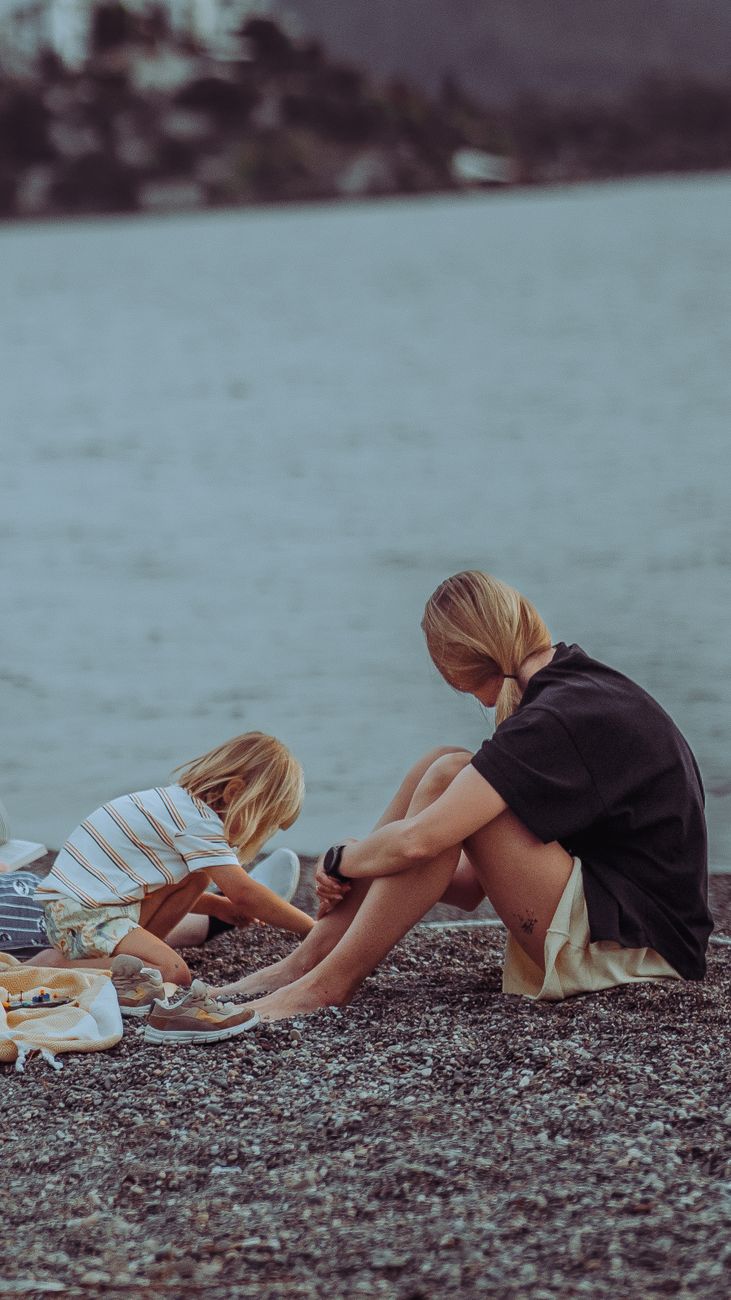 blonde mother sitting with daughter by river